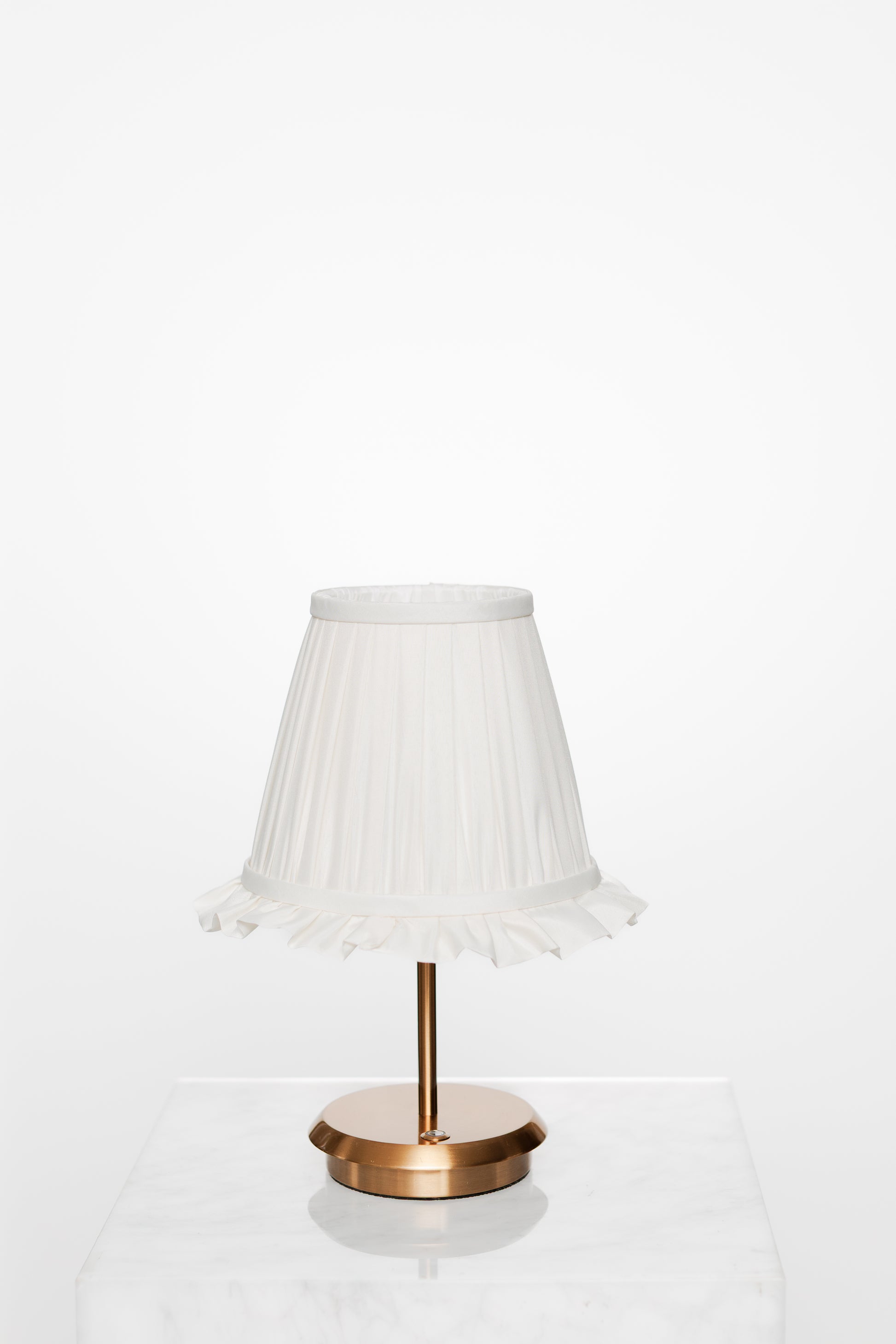 Neutral-toned room corner with armchair, brass lamp, and greenery outside.