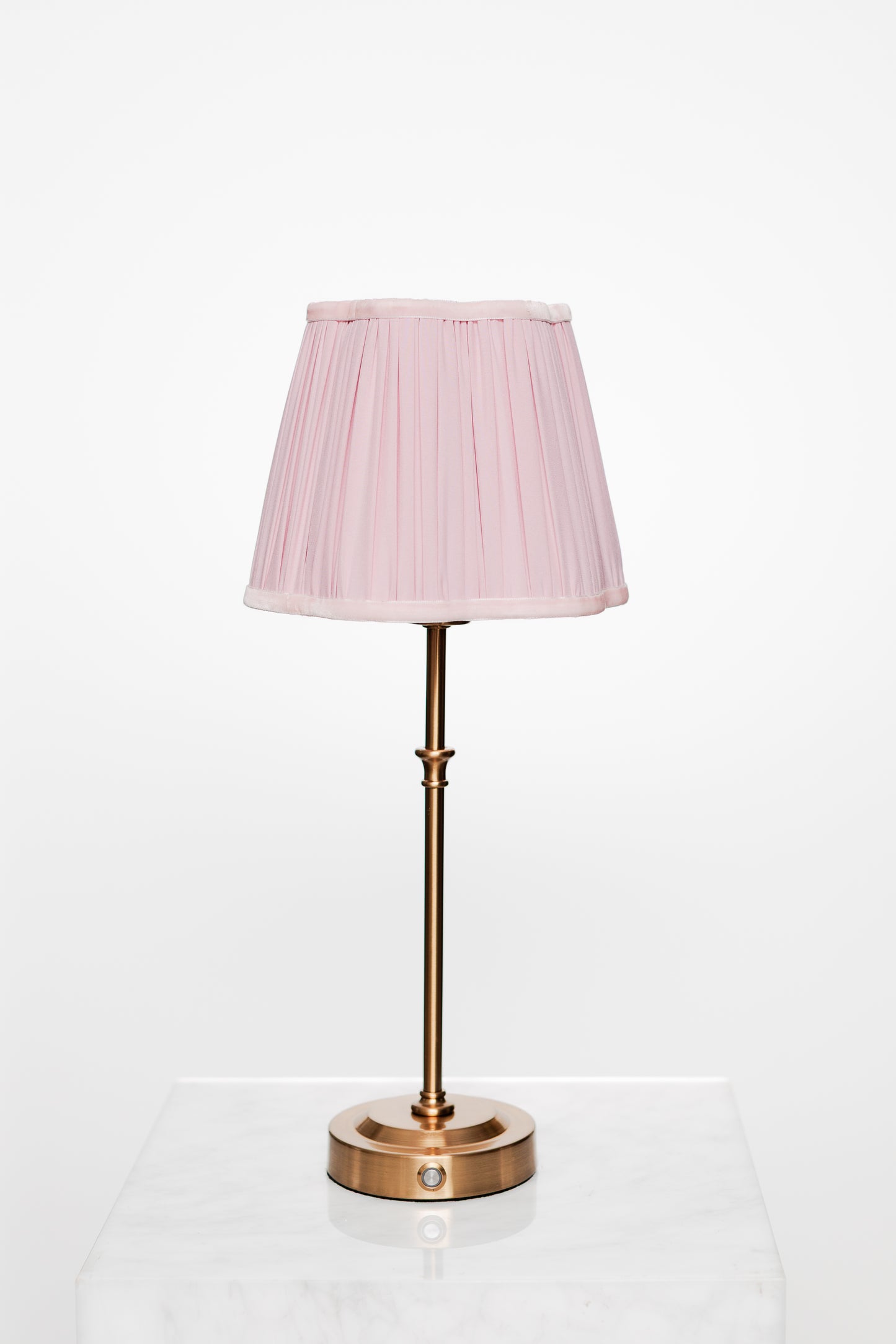 Minimalist corner with brass lamp, light wood surfaces, and book.