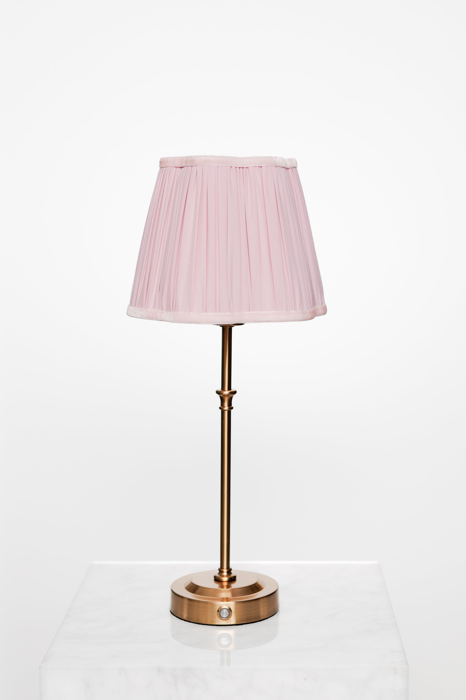 Minimalist corner with brass lamp, light wood surfaces, and book.